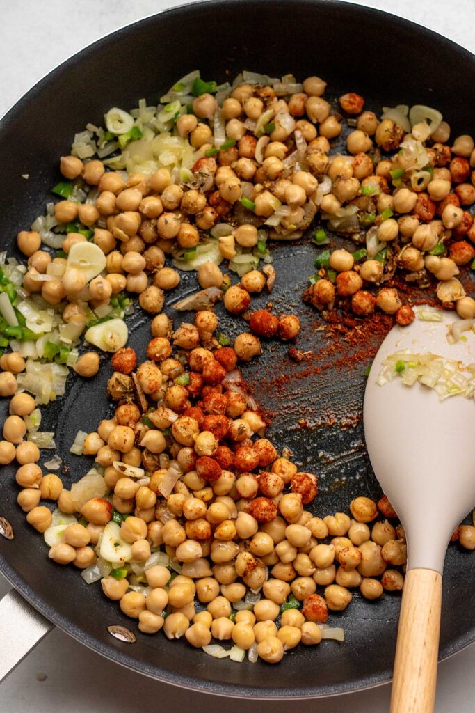 Sauteing the chickpeas with spices in a pan.