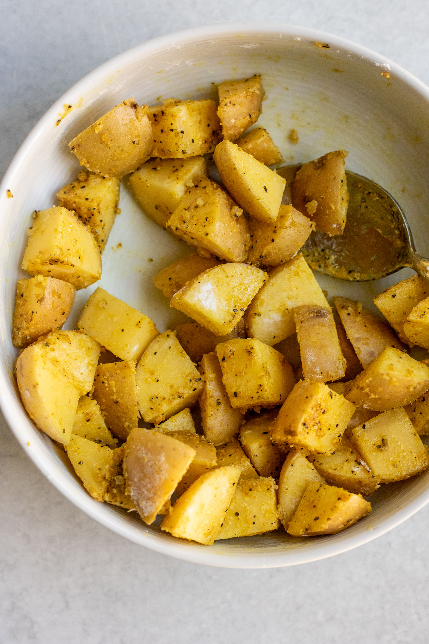 Freshly cut potatoes placed in a bowl and coated in adobo seasoning.