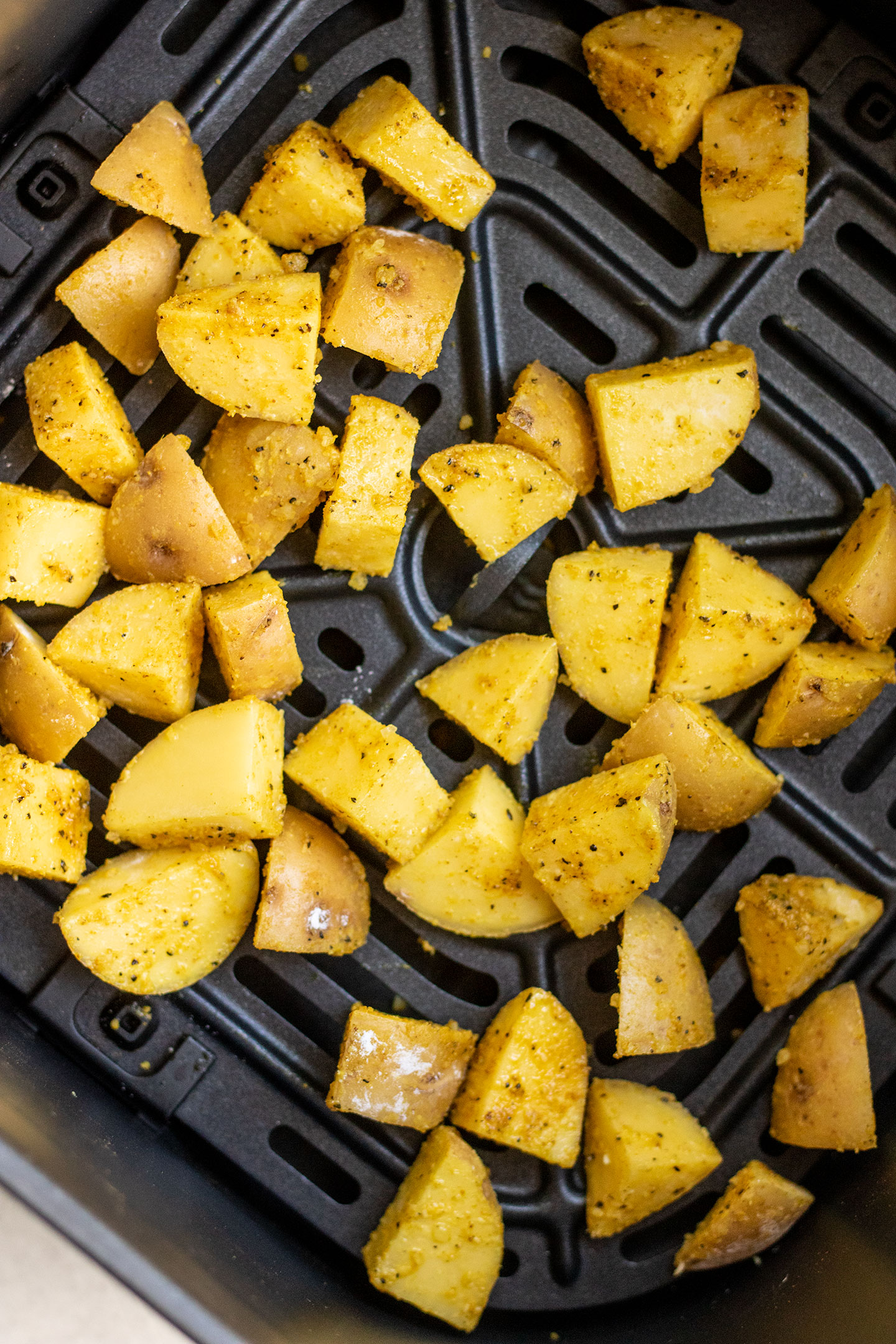 Adding the adobo coated potatoes to an air fryer.