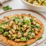 Flatbread topped with a mix of avocado and white beans with the bean mix featured in the background.