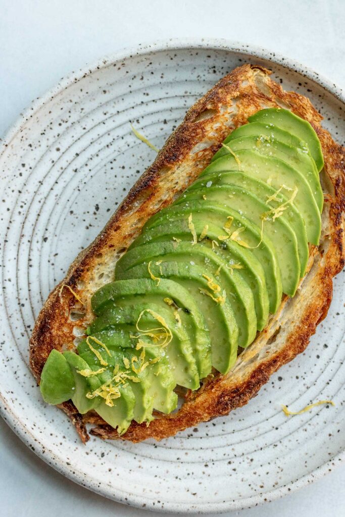Toast topped with avocado slices and lemon zest.