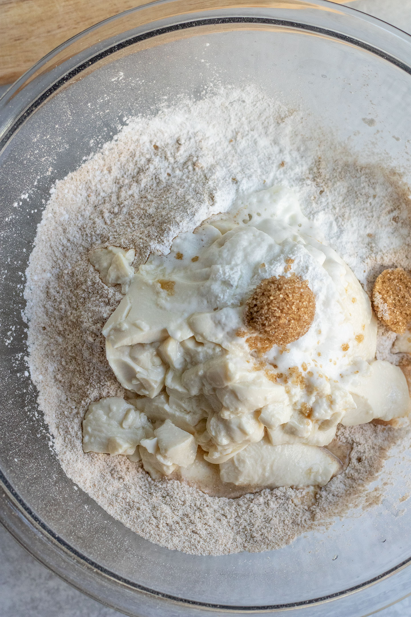 Mixing the spelt flour, brown sugar, tofu, and baking powder together in a glass mixing bowl.