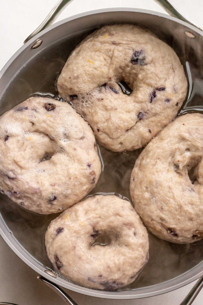 Bagels boiling in a water bath.