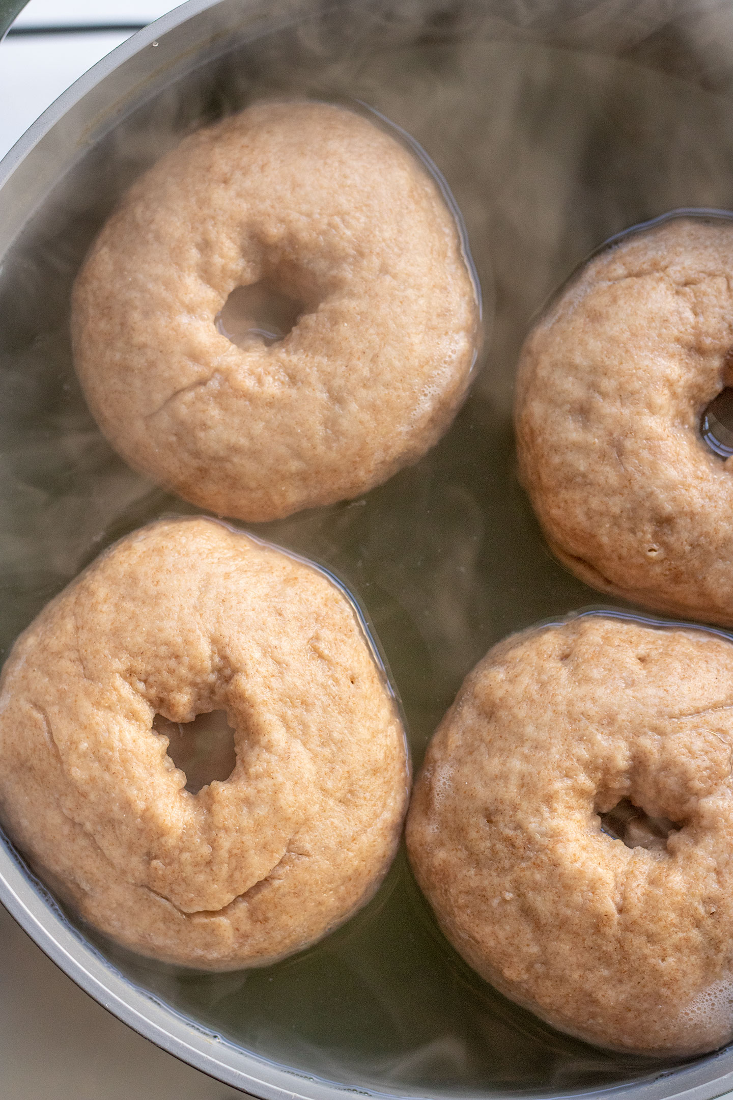 The bagels rising to the top of the water bath as they cook.