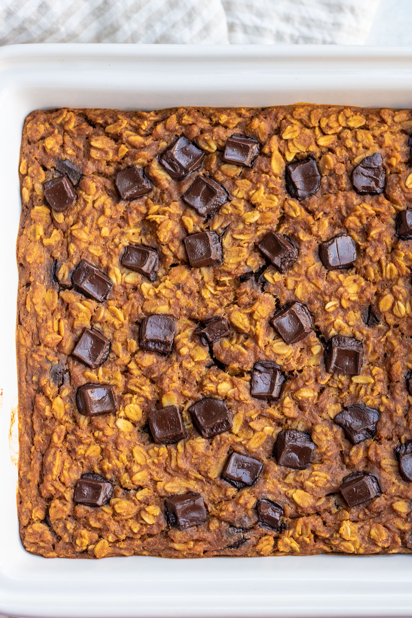 Baked pumpkin oatmeal right out of the oven in a white ceramic baking dish.
