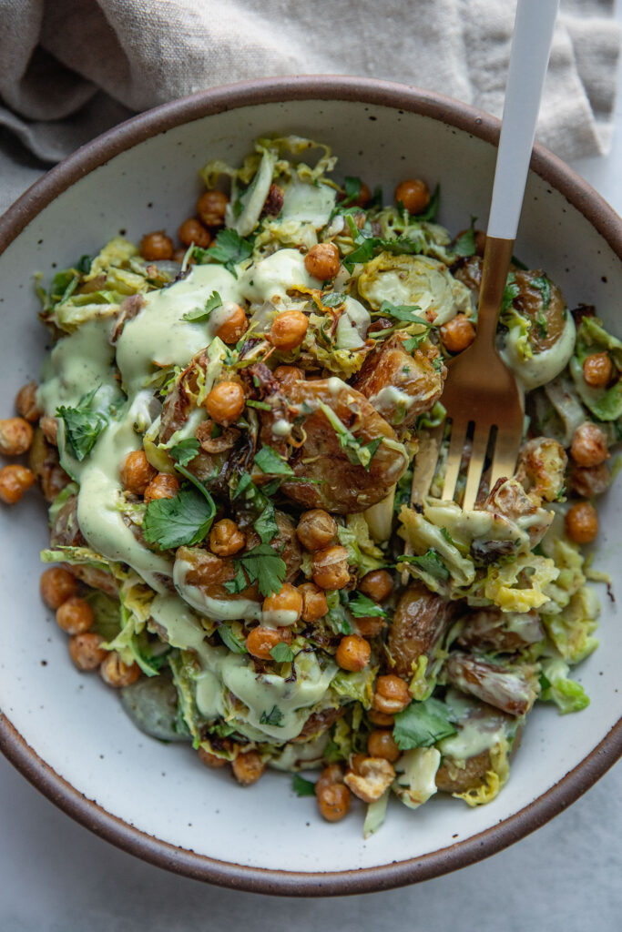 Eating the baked brussels sprout and potato salad from a bowl with a fork.