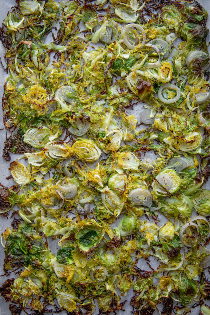 Roasted brussels sprouts and shallots on a baking tray.