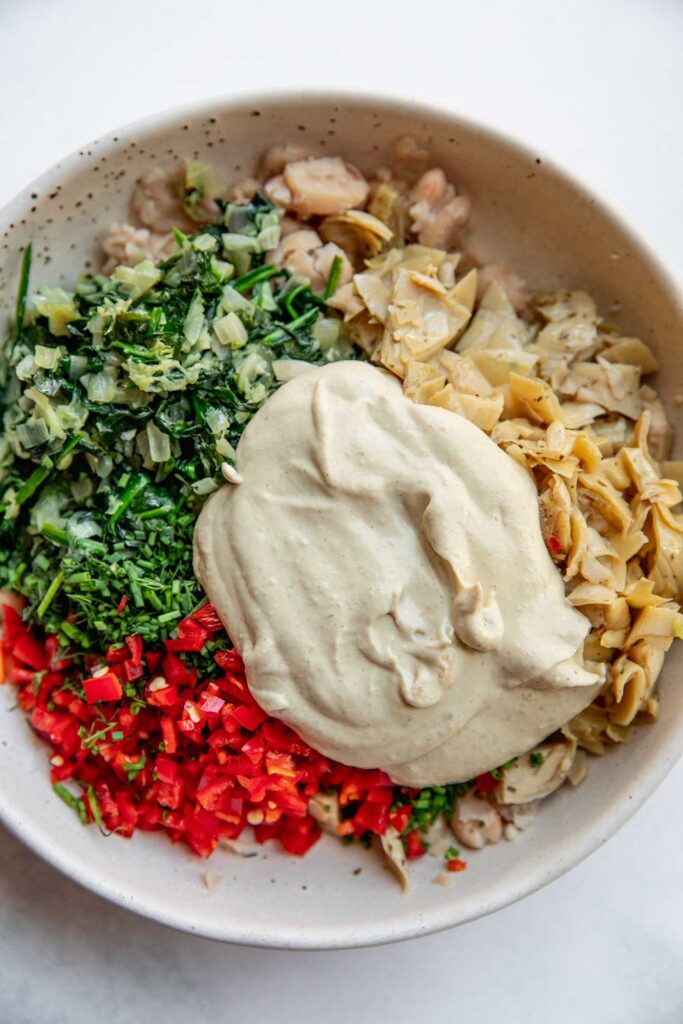 Bowl of beans, spinach and artichokes topped with the cashew cream sauce.