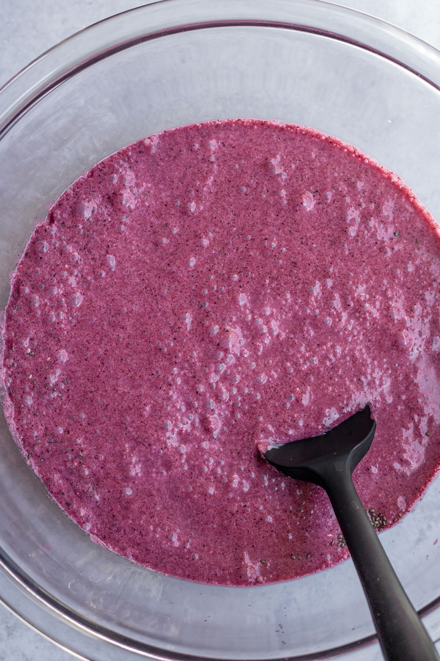 Mixing the chia seeds together with the blueberry milk in a large glass mixing bowl.