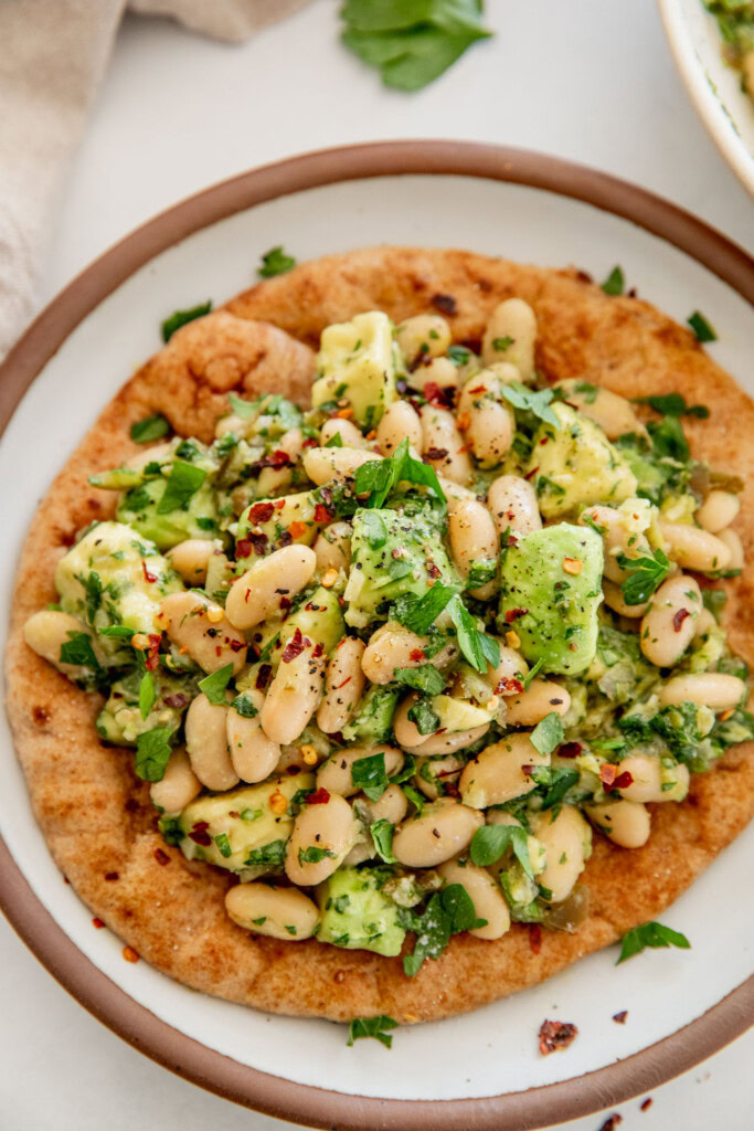 Top down view of a flatbread topped with an avocado white bean mix.