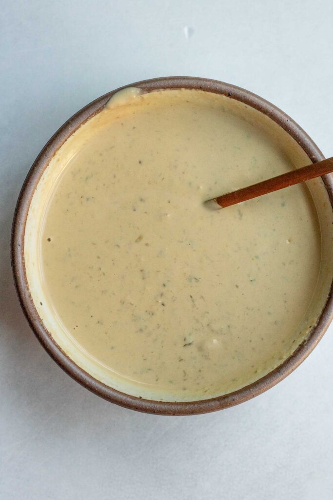 Creamy tahini Caesar dressing mixed in a white bowl.