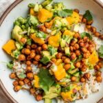 Top down view of a bowl of tofu rice topped with mango salad and crispy chickpeas.