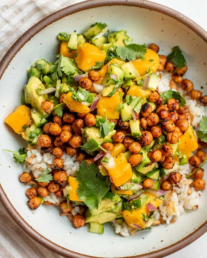 Top down view of a bowl of tofu rice topped with mango salad and crispy chickpeas.