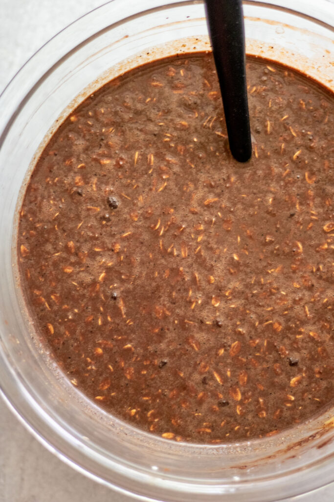 The chocolate oat batter fully mixed in a glass mixing bowl.