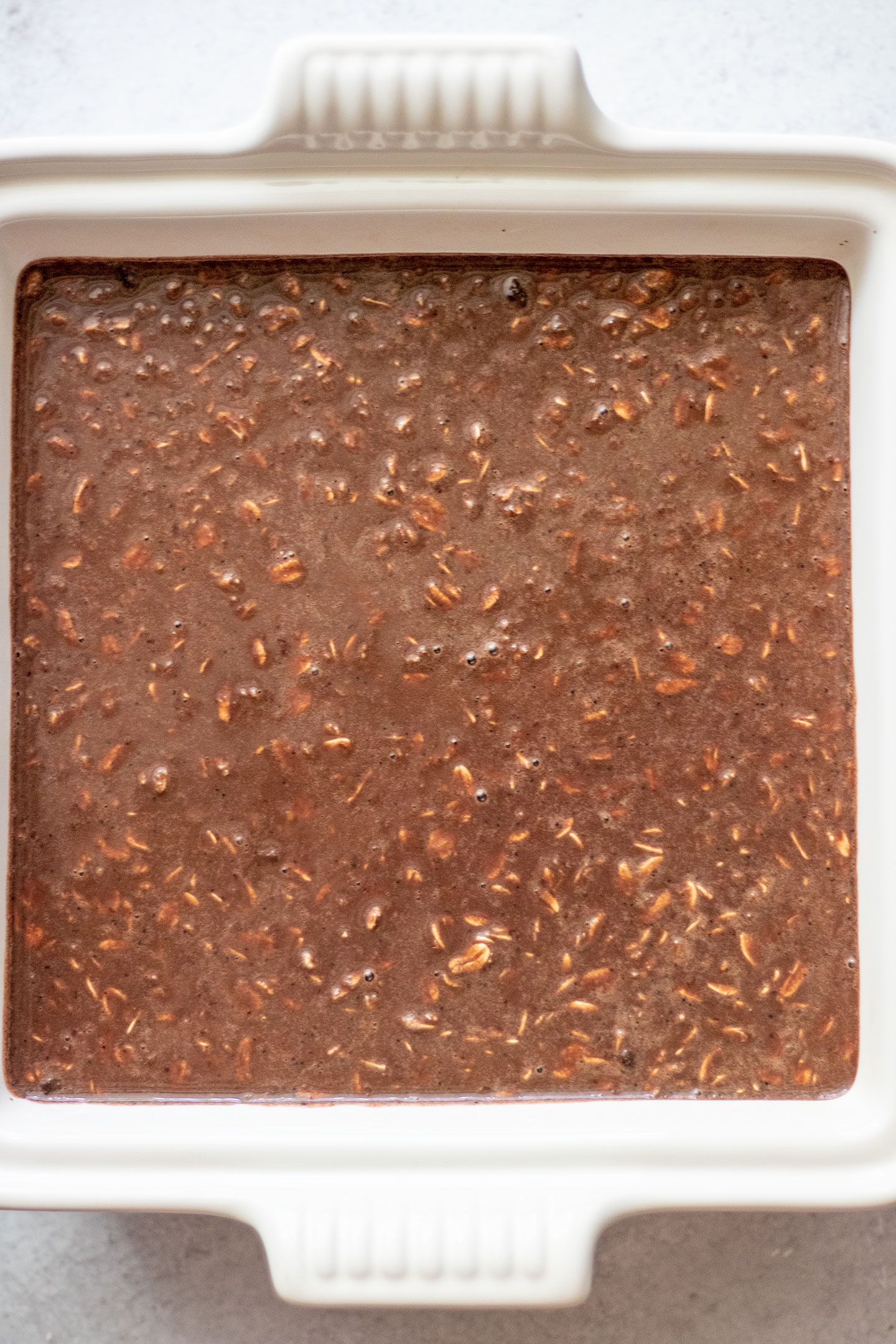 Adding the batter to a ceramic baking dish.