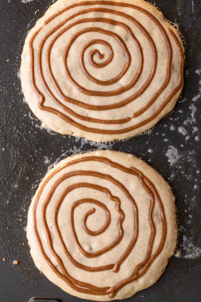 Adding the swirl to the wet side of pancakes on a greased griddle.