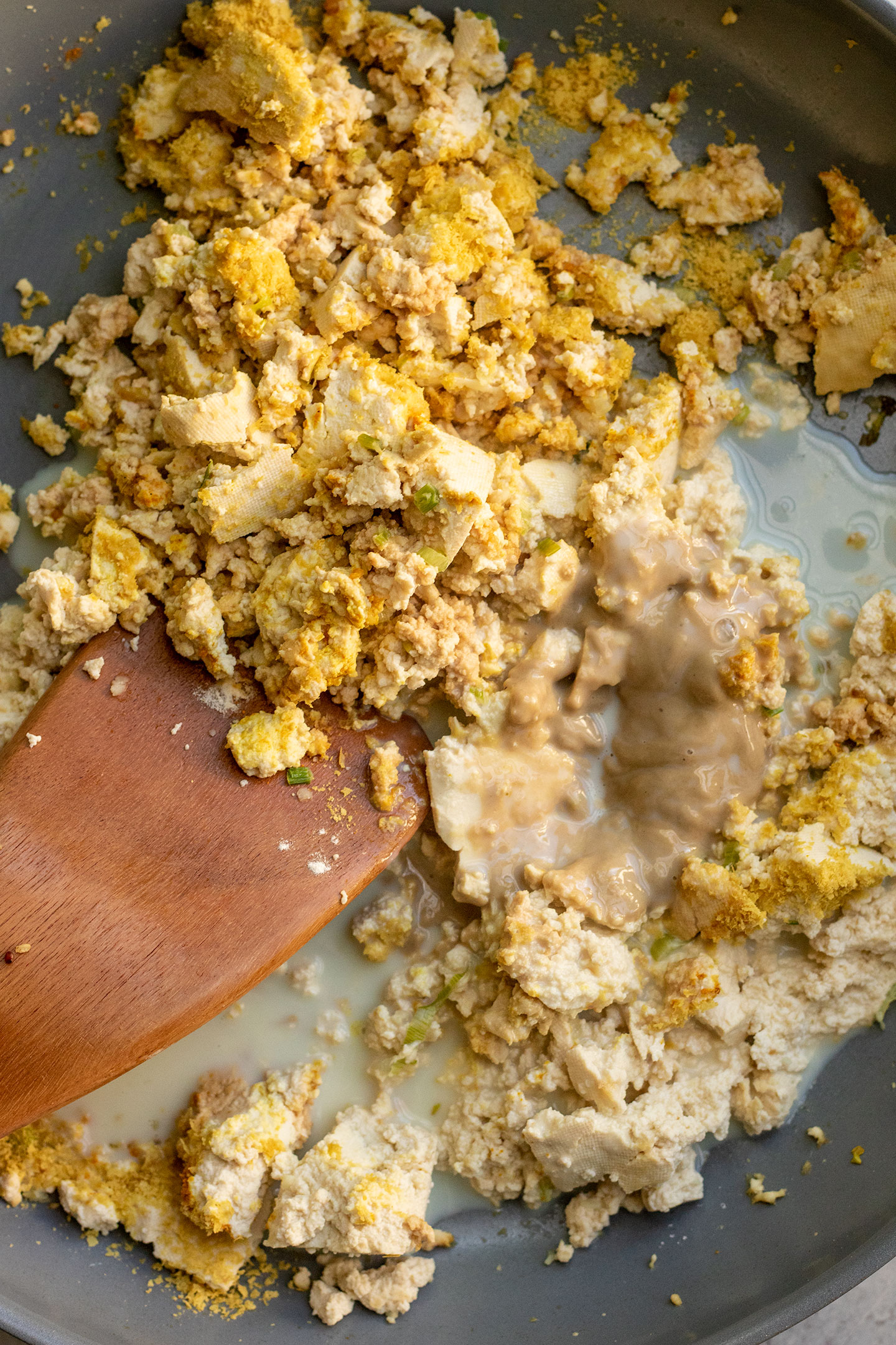 Mixing the sauteed tofu with the tahini, nutritional yeast and milk.