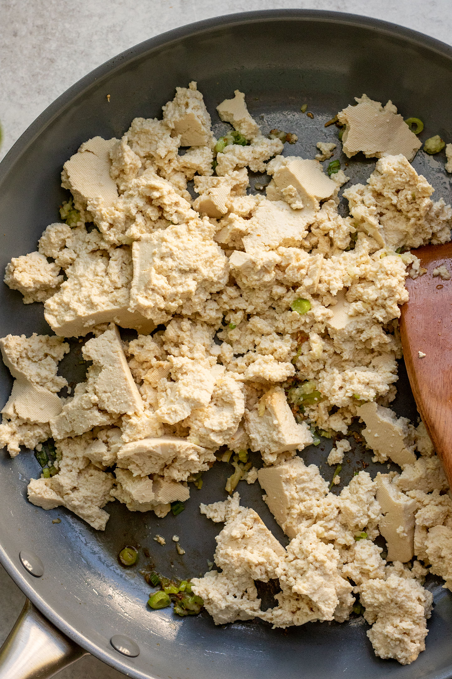 Sauteing the tofu in a pan with scallions and garlic.