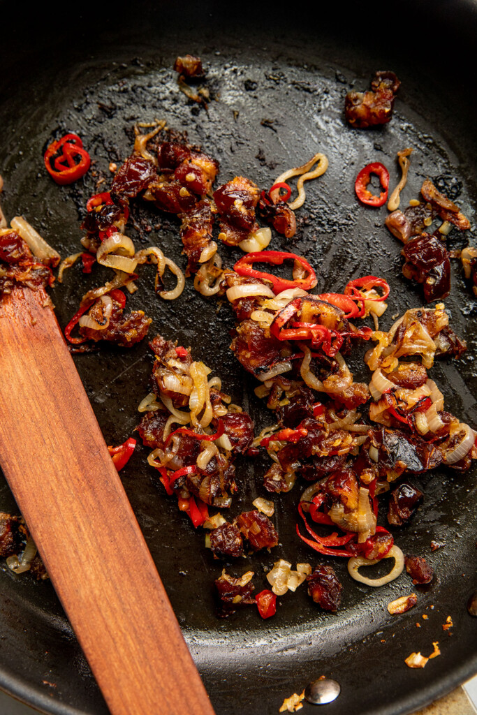Sauteed dates, shallots and pepper in a pan.