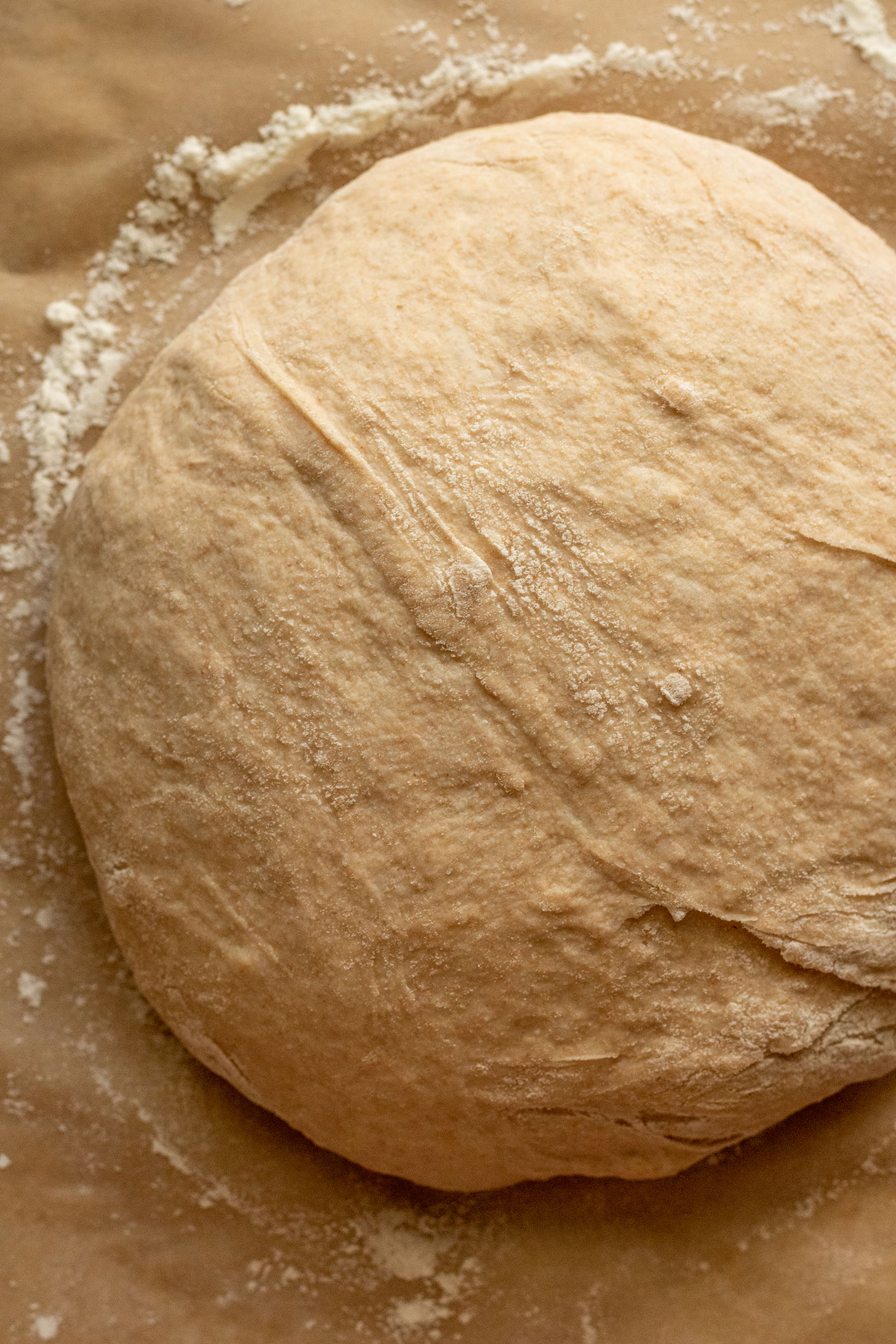 Dough resting on a floured piece of parchment paper.