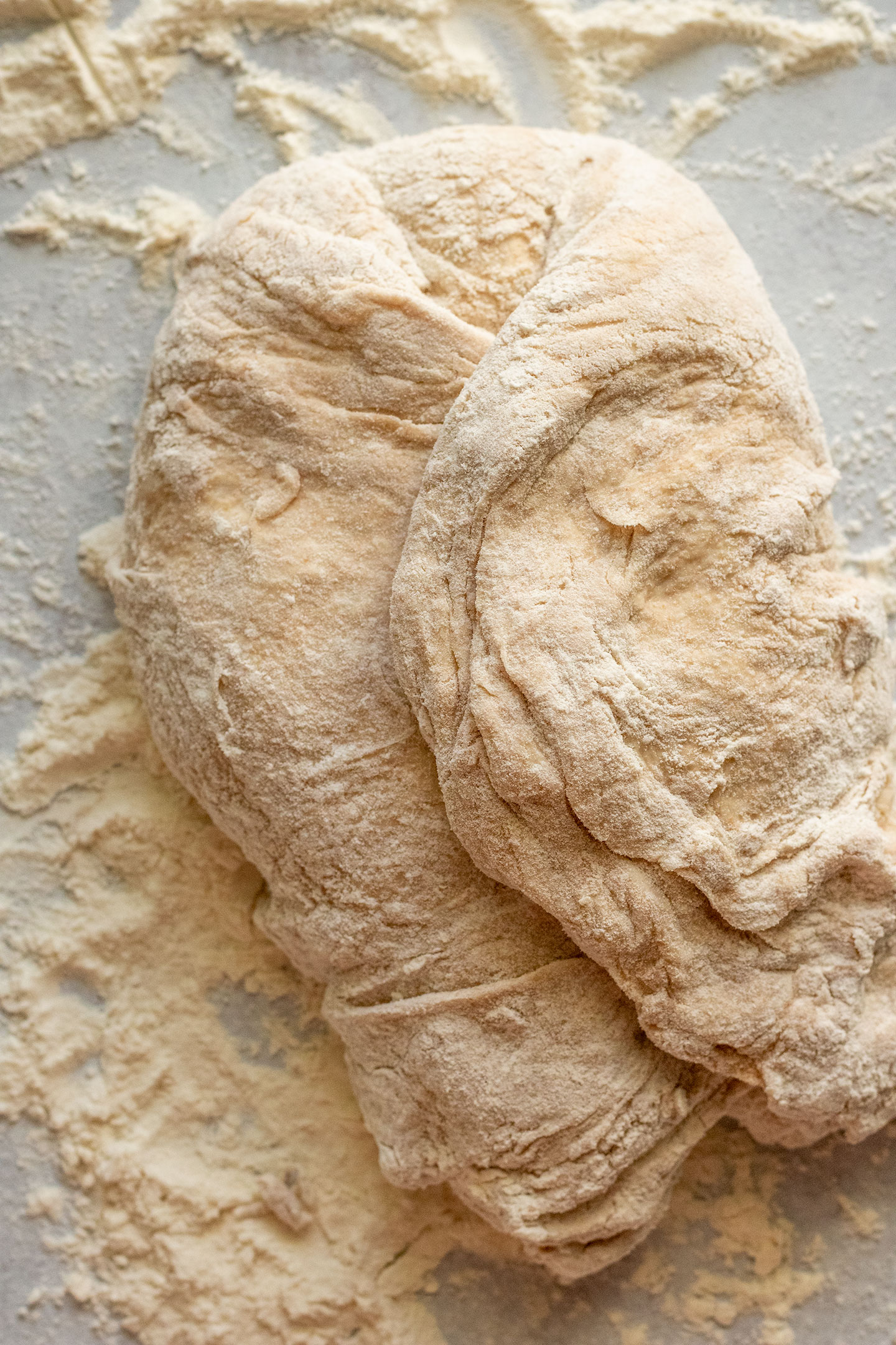 Folding the dough towards the center to form a round dough ball.