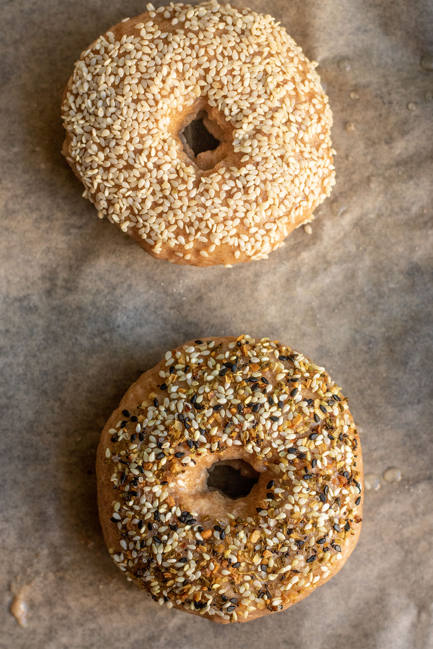 Coating the spelt bagels with sesame seeds and everything bagel seasoning and placing on a parchment lined tray for baking..