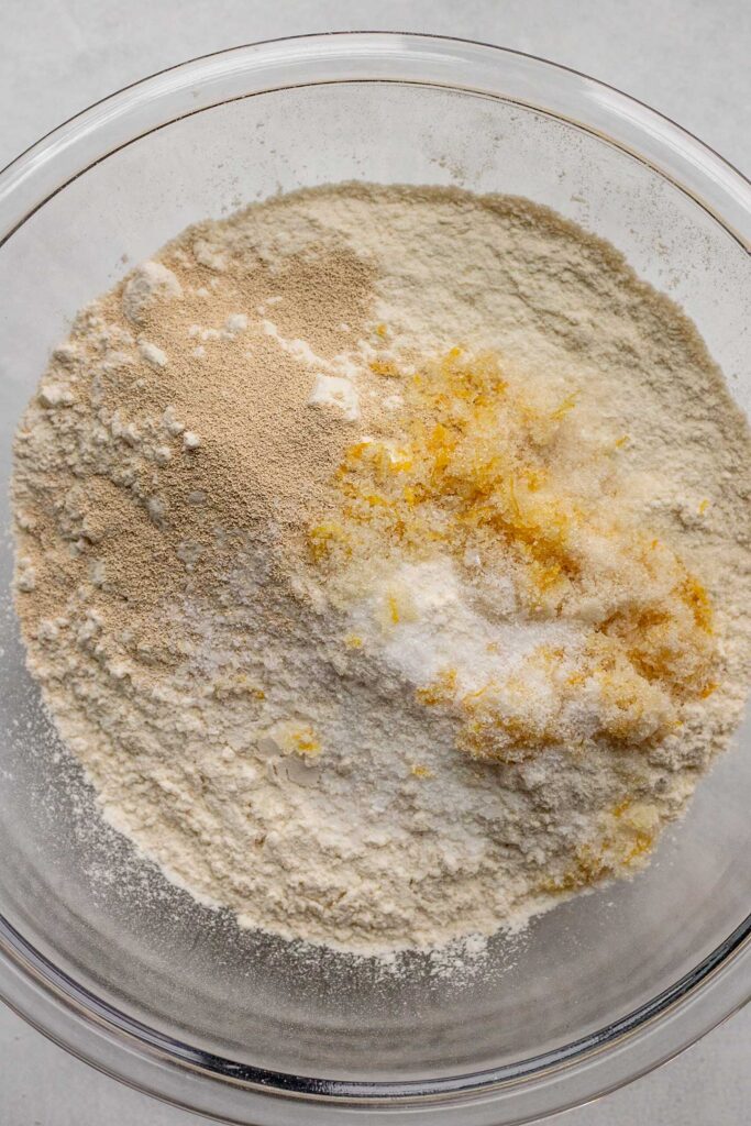 Flour, sugar, lemon zest and yeast in a glass bowl.