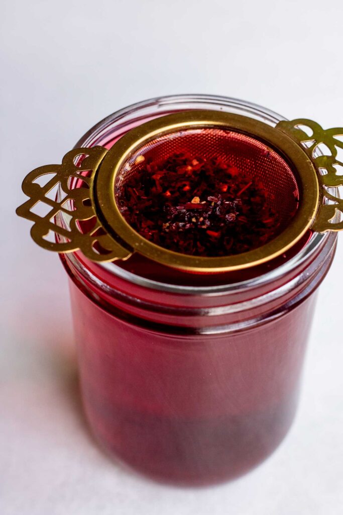 Steeping hibiscus tea leaves in a tea infuser.