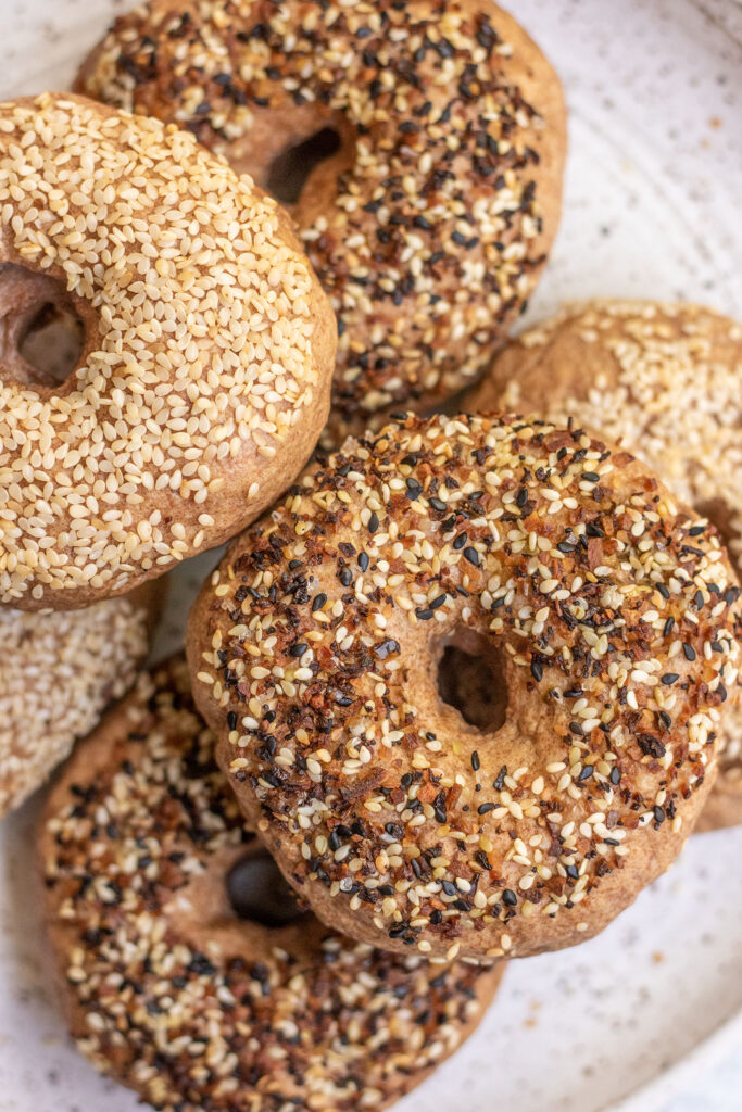 The sesame and everything high protein bagels stacked on a plate.