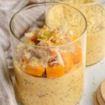 Two jars of mango flavored overnight oats topped with cubed mango, lime zest and coconut flakes.