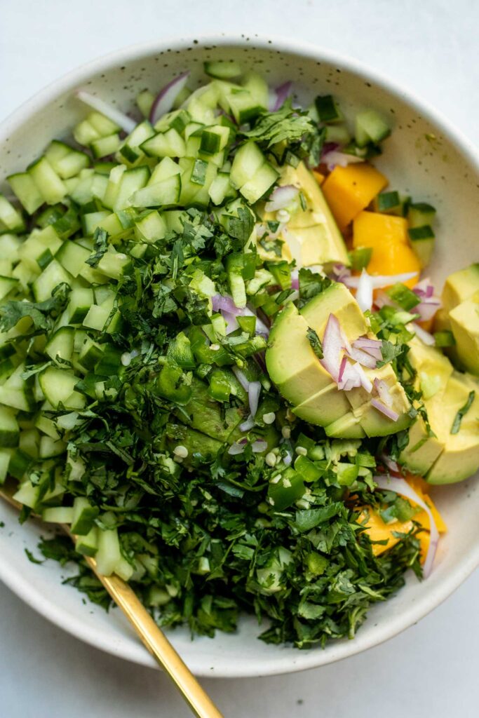 White bowl filled with tofu rice and topped with a mango salad and crispy chickpeas.