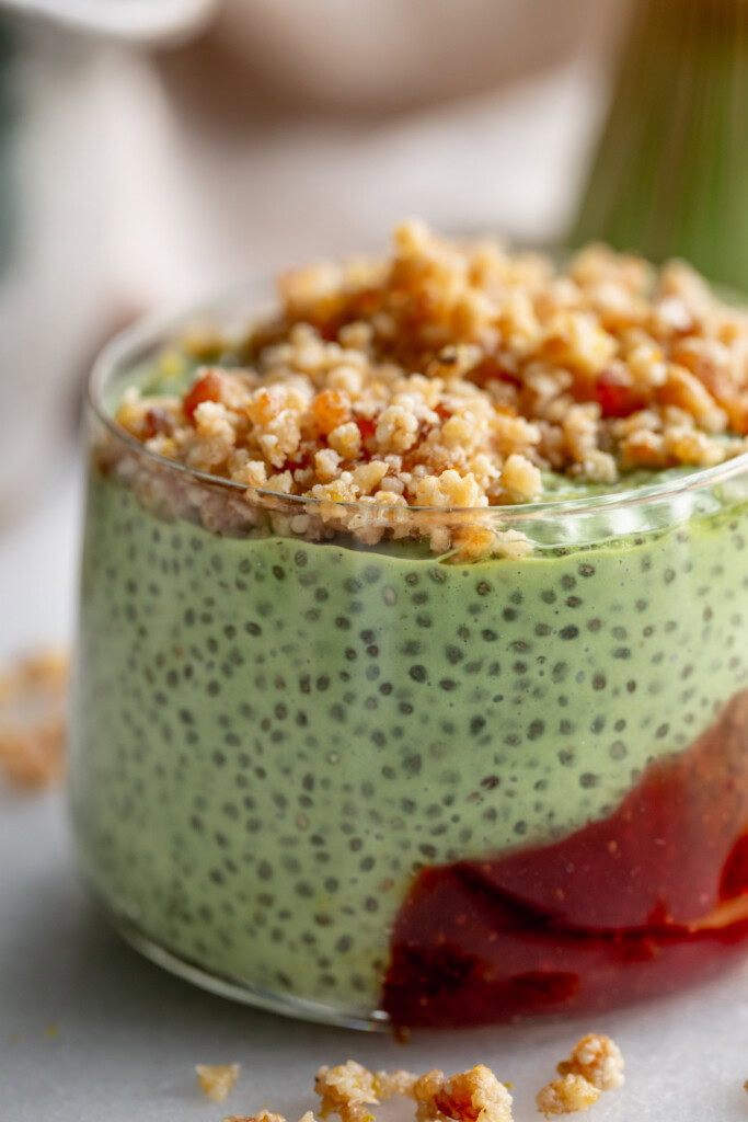 Close up of a cup filled with strawberry jam, matcha chia pudding, and pie crust crumble on top.