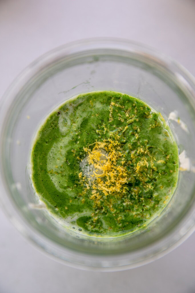 Matcha, milk, lemon zest, syrup, cream cheese, and yogurt in a blender cup.