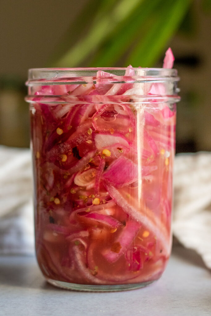 Front on view of a jar stuffed with pickled red onions.