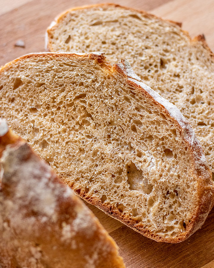 Freshly sliced whole wheat no knead bread on a wooden cutting board.