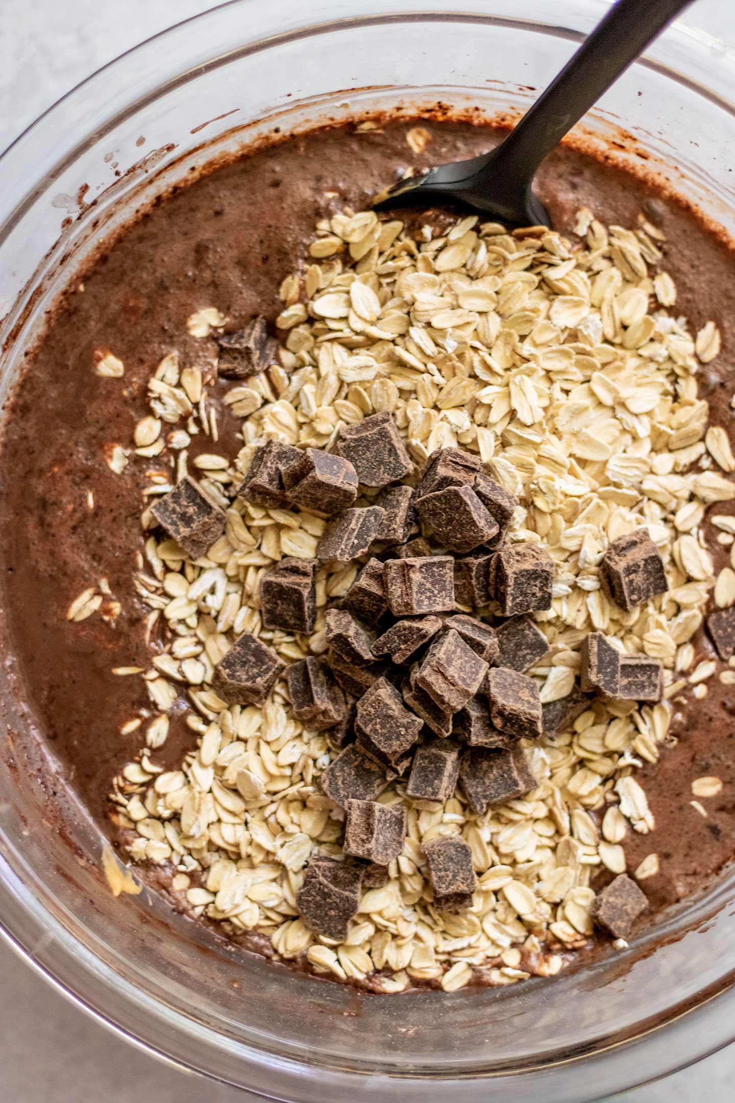 Folding in the oats and chocolate chunks into the chocolate batter.