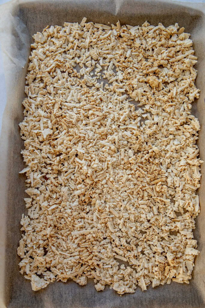 Shredded seasoned tofu on a parchment paper lined baking tray.