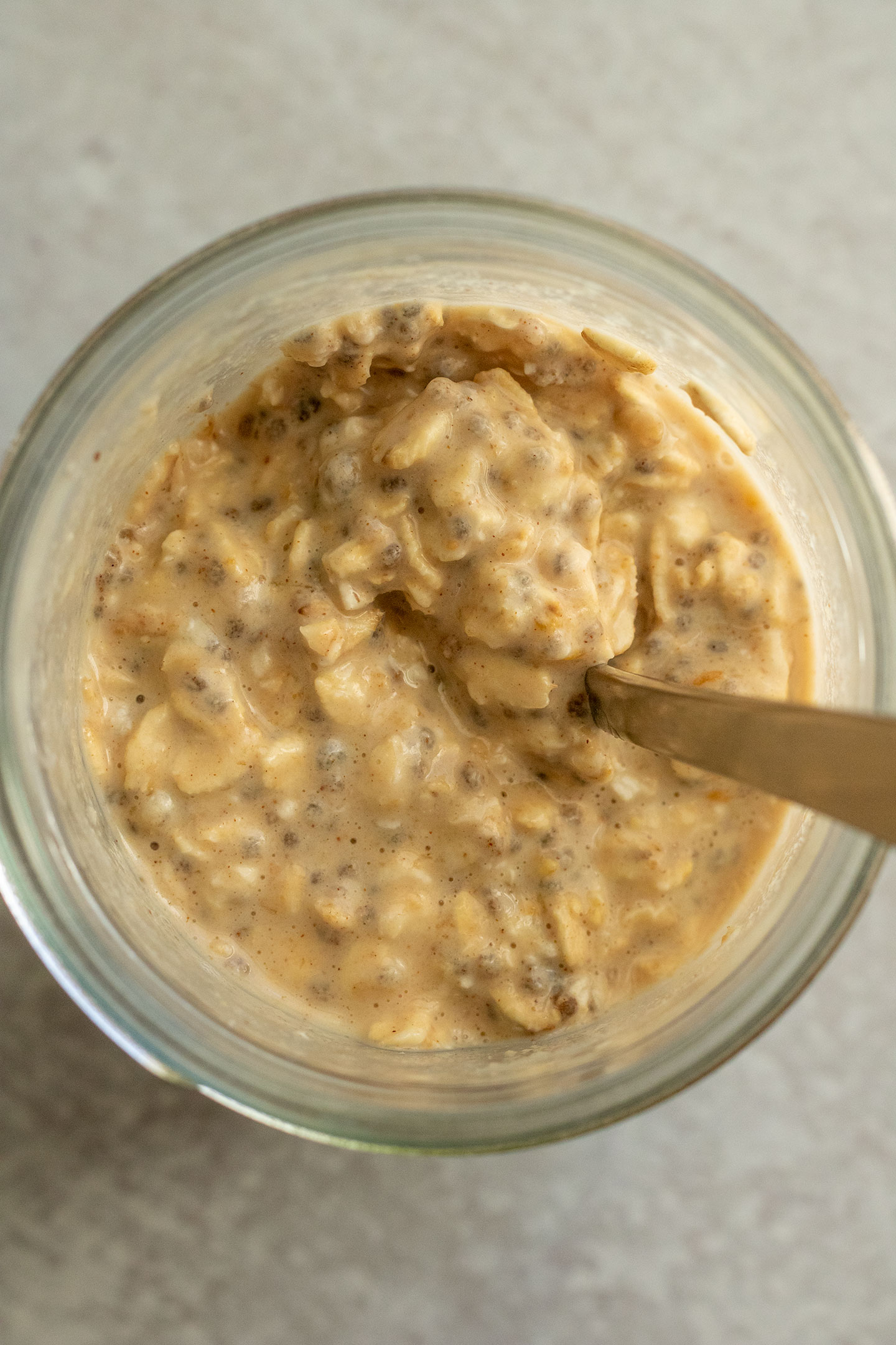 The oats after mixing together with the wet ingredients with a spoon in a jar.
