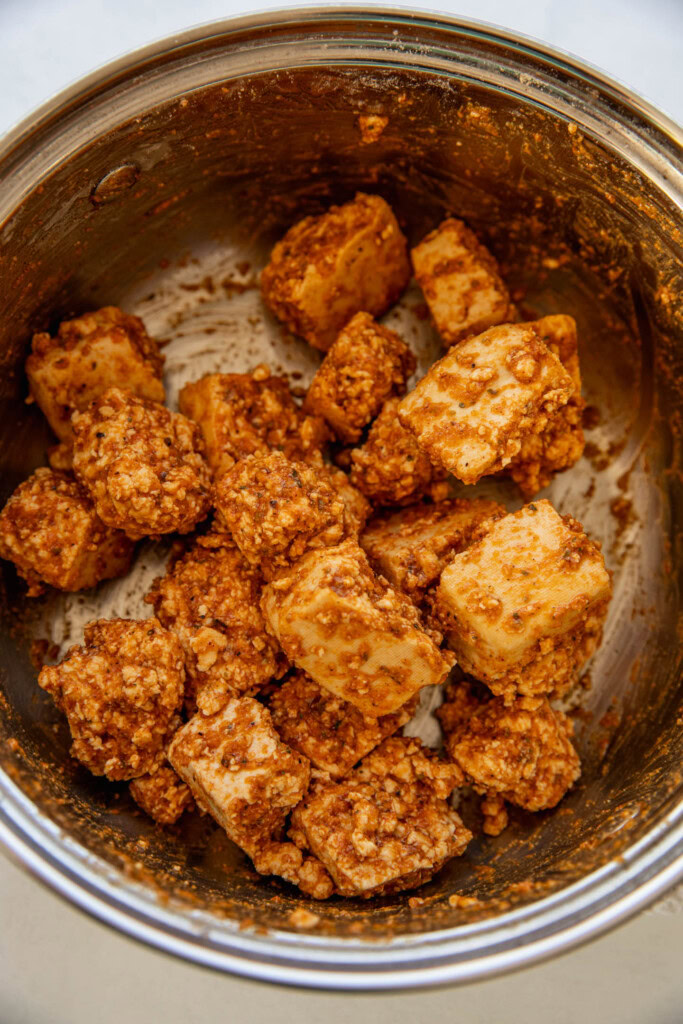 Tofu coated in seasoned flour and oil in a pot.