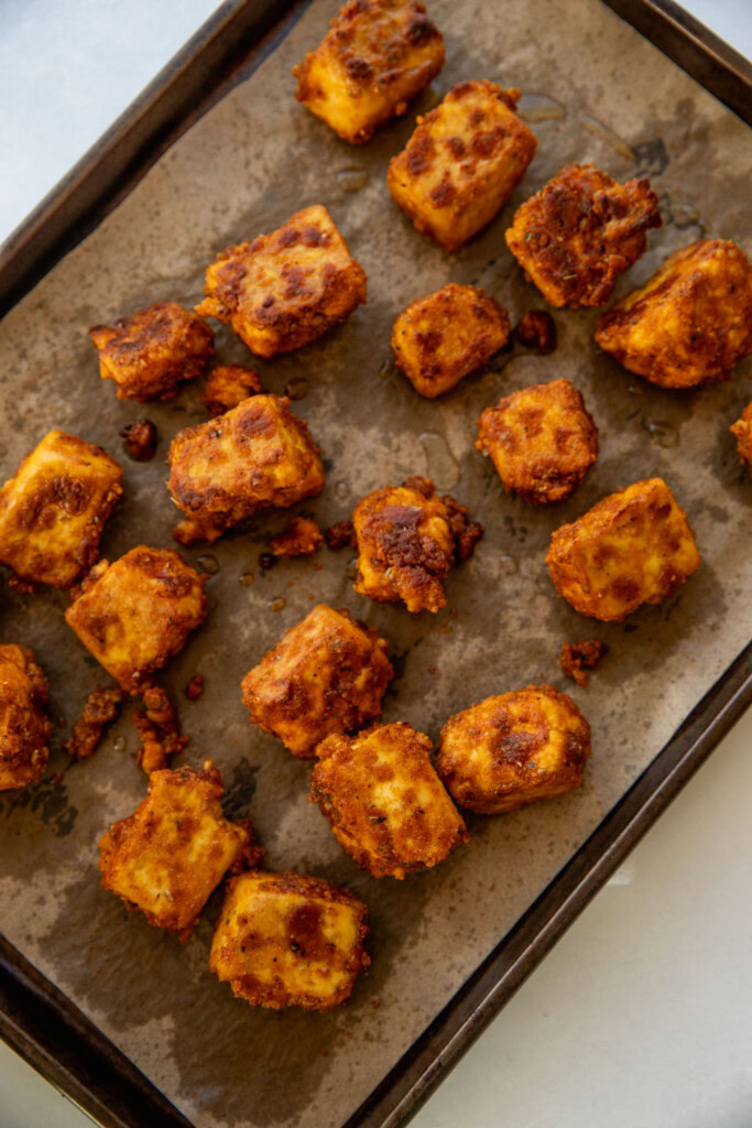 Drizzling a little more oil to the tofu bites after baking the oven for 20 minutes.