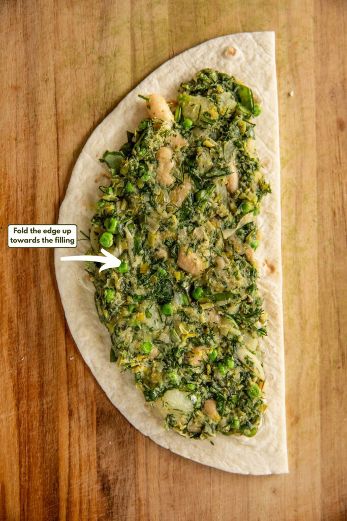 A tortilla half filled with the potato leek mixture with an empty centimeter border around the filling.
