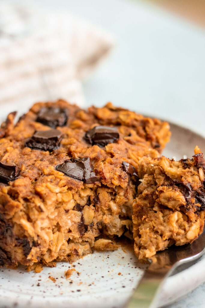Cutting a piece of pumpkin baked oatmeal from a plate with a fork.