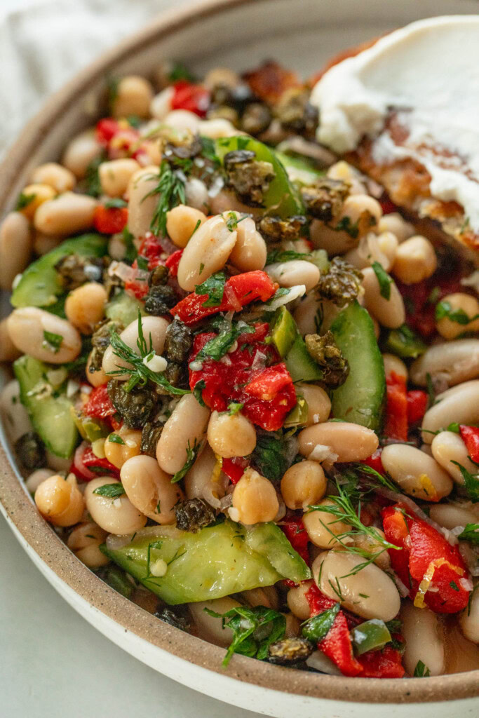 Close up of a bowl of bean salad topped with fried capers.