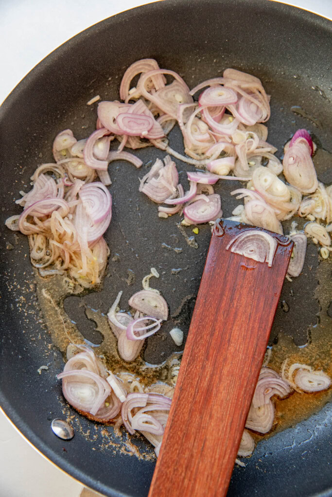 Sauteing shallots and coriander in oil in a pan.