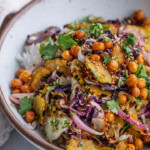 Close up of a bowl of rice topped with mixed roasted cabbage, squash, chickpeas and marinated onions.