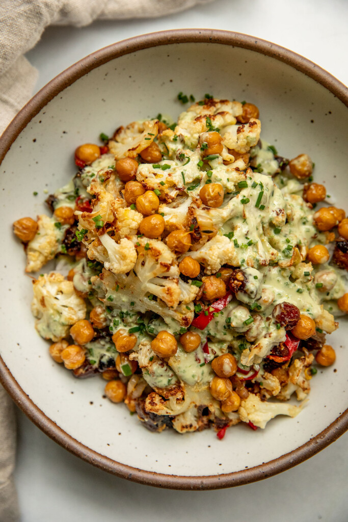 Bowl of rice topped with roasted cauliflower, chickpeas, dates and a creamy chive dressing.
