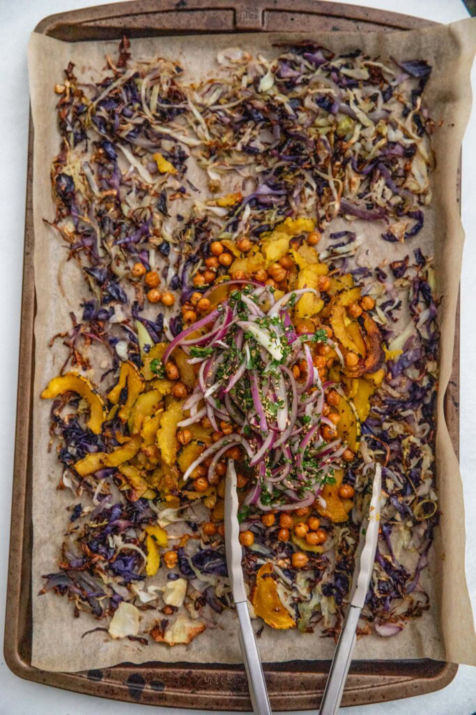 Transfering squash, chickpeas and marinated onions the the tray of roasted cabbage.