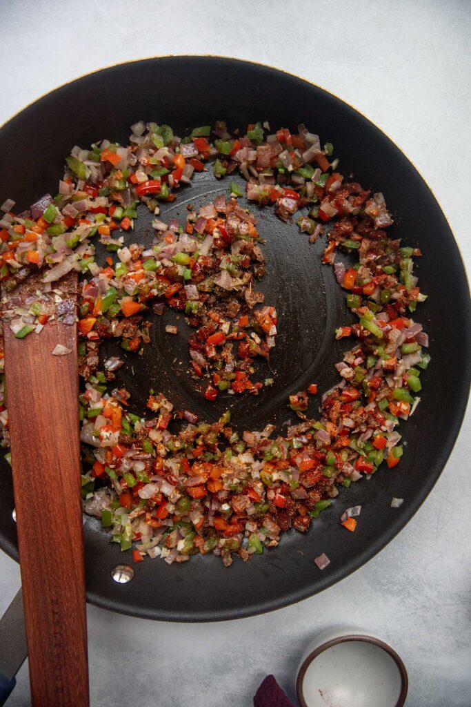Sauteing the onions and peppers together in a pan.