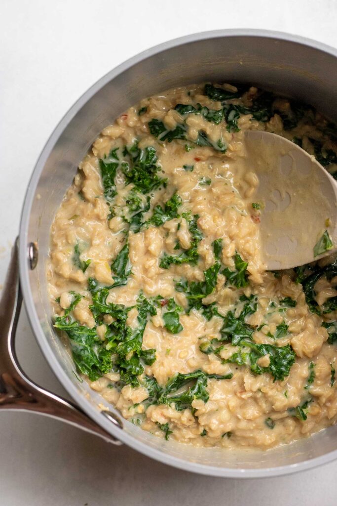 Mixing chopped kale into the miso infused oatmeal.