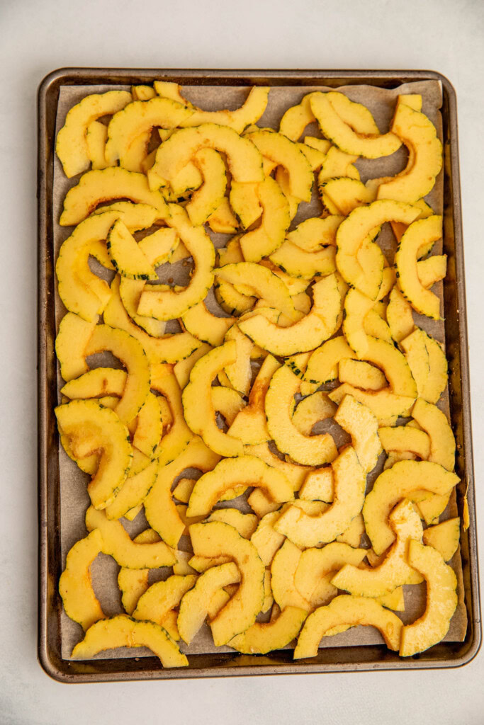 Seasoned squash slices on a baking tray.